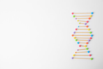 DNA molecule model made of toothpick and colorful beads on white background, flat lay. Space for...