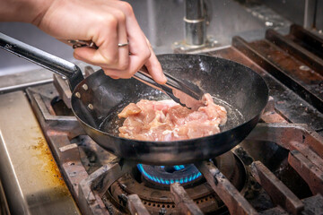 chef cooks chicken　厨房で鶏肉を炒めている