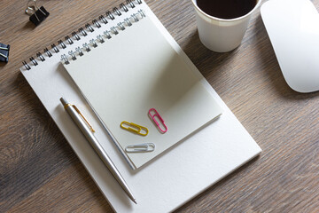 Notebooks, paper clips with a pen and coffee, on a wooden table with a keyboard and mouse