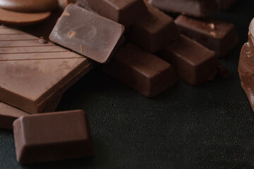 Pieces dark chocolate on black background. Closeup view shot.