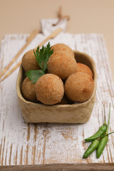Croquette in ceramic square bowl on white wooden board, isolated
