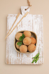 Croquette in ceramic square bowl on white wooden board, isolated