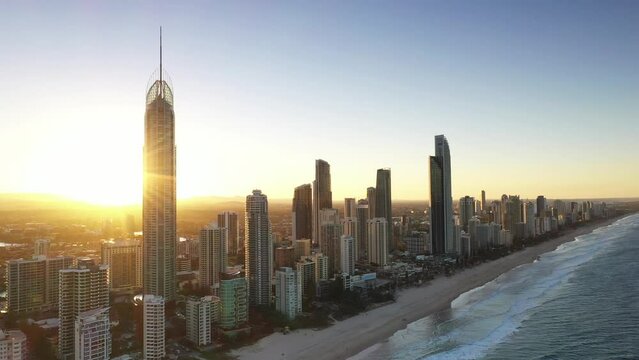 Aerial sunset view circling around from ocean to beach with Surfers Paradise cityscape. Gold Coast, Australia