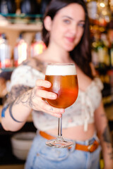 close-up with out-of-focus background of a beer being offered by a pretty waitress
