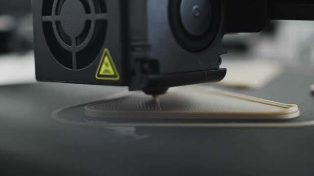 Closeup of 3d printer nozzle, heating block, motor laying down rows of filament