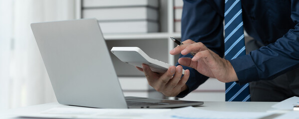 business people working on laptops Use a calculator to do calculations at the office, analyzing business documents with graphs. Financial charts. Market reports. Business discussion management concept