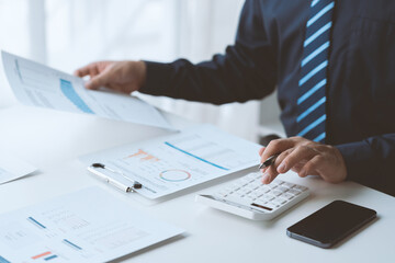 Businessman working in office using calculator to calculate numbers, financial accounting concept for company progress and growth management system concept finance and tax.