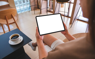 Mockup image of a woman holding digital tablet with blank white desktop screen in cafe