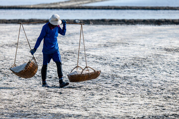Worker carrying wooden baskets in salt field at Phetchaburi Thailand Worker carrying wooden baskets in salt field at Phetchaburi Thailand 