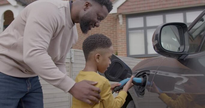 Father and Son Charging Electric car at home before Road trip