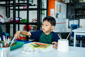 Cute little asian boy kids doing art painting activities in the classroom on the table, Indonesian,...