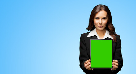 Fototapeta premium Portrait of serious brunette businesswoman showing tablet pc, touchpad, with green chroma key screen, on sky blue background. Confident attractive business woman at office.