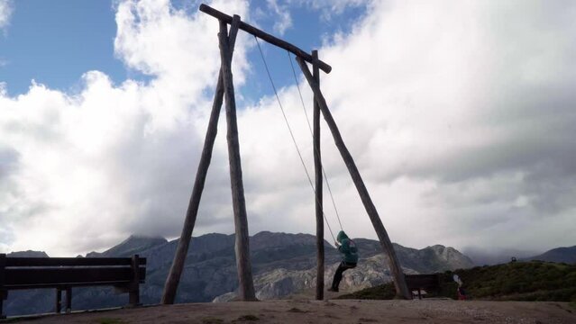 Wide shot of a female swinging in a large swing set in the nature in Asturias.