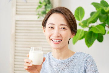 自宅で牛乳を飲む女性　カメラ目線