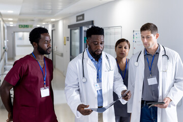 Diverse male and female doctors with stethoscopes inspecting xray on corridor