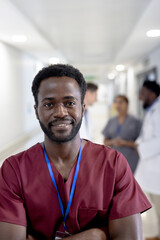 Portrait of happy african american male doctor with arms crossed over diverse colleagues