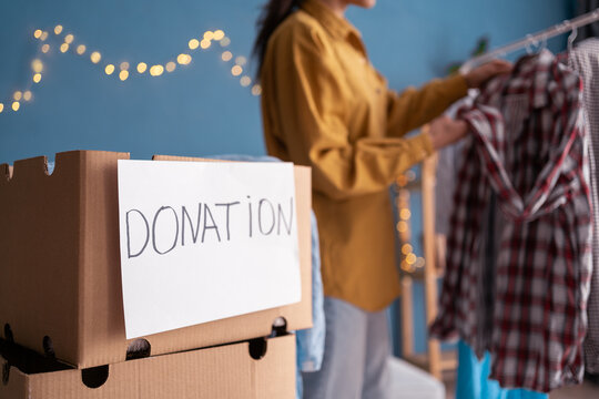 Woman packing clothing donation box on home room background
