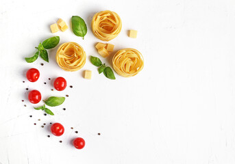 Pasta ingredients on white background. Red cherry tomatoes, basil, peppercorns. Italian cuisine concept. Healthy vegetarian diet. Flat lay, copy space