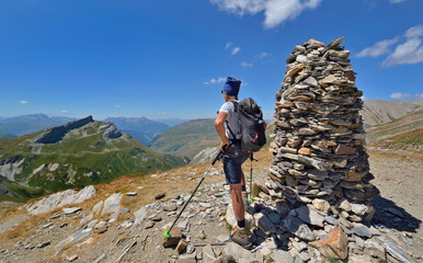 hiker standing and overlooking the mountains a hiking  trail  next to a  big cairn the tour of Mont...