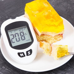 Glucose meter for checking sugar level and creamy sweet sponge cake with layers and jelly....