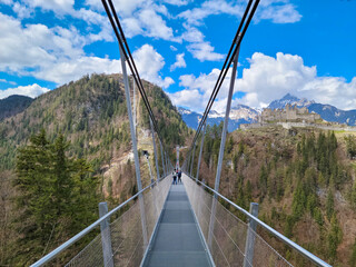 Pedestrian Swinging Bridge in Austria, with Historic Castle and Alps in Background	