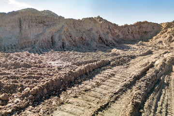 Open sand pit, for sand extraction during construction. The texture of sand and traces of the tread of large cars. Sand for construction work. Storage of sand at the construction site.