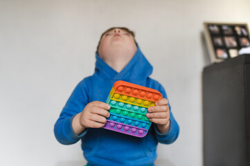 child hides his face behind a toy and plays with pop it toy. Sensory game antistress fidget closeup. Selective focus on toy. Autism concept.
Autism Spectrum Disorder and Adjustment Difficult