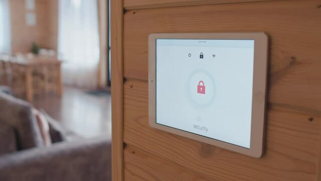 Selective focus shot of Caucasian woman going outside turning on security system on smart home controller