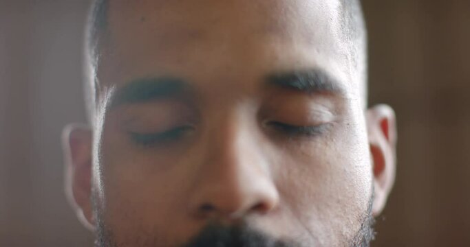 Portrait close up of focused biracial man opening eyes and looking to camera in slow motion