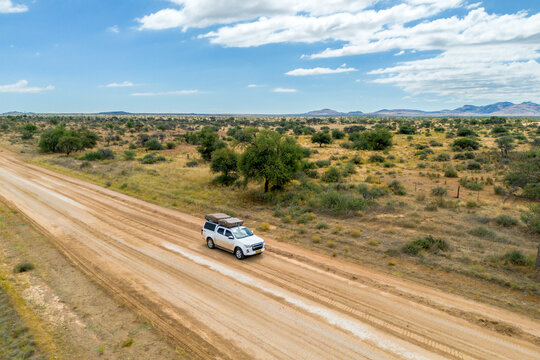 Drone image of offroad vehicle driving on dirt road in African bush