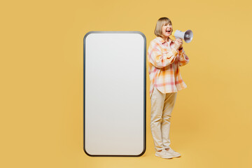 Full body elderly blonde woman 50s years old wear casual clothes big huge blank screen mobile cell phone smartphone with area scream in megaphone isolated on plain yellow background studio portrait.