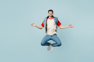 Fototapeta na wymiar Full body young man wear denim vest red t-shirt casual clothes hold spread hands in yoga om aum gesture relax meditate try calm down isolated on plain pastel light blue background. Lifestyle concept.