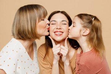 Close up happy lovely women wear casual clothes with kid girl 6-7 years old. Granny mother daughter holding hands kiss mommy close eyes isolated on plain beige background. Family parent day concept.