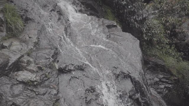 Slowmotion shot of water of a waterfall coming down over the rocks on a grey day LOG