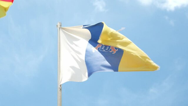 National state flag of Canary islands wave on windy day against blue sky