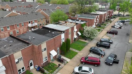 Close up aerial of low income housing in urban city during spring. Cars parked outside of houses with cop cruiser. Poverty and dangerous neighborhood theme.