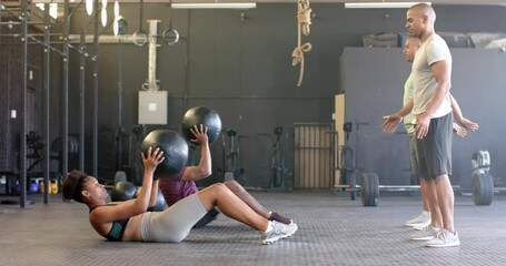 Diverse group fitness class training in pairs with medicine balls at gym, in slow motion - Powered by Adobe