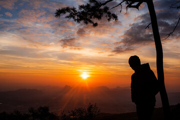 Silhouette of tourists watching the sunrise at Pha Nok Aen View Point Phu Kradueng National Park, Thailand