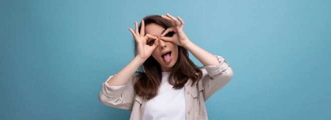 panoramic photo of a joyful cheerful brunette young female adult in a shirt and jeans on a background with copy space