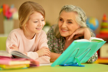 Fototapeta premium Grandmother with cute little girl doing homework