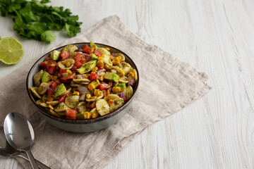 Homemade Grilled Corn Summer Pasta Salad in a Bowl on a white wooden background, low angle view. Copy space.