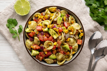 Homemade Grilled Corn Summer Pasta Salad in a Bowl on a white wooden background, top view. Flat lay, overhead, from above.