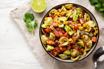 Homemade Grilled Corn Summer Pasta Salad in a Bowl on a white wooden background, top view. Flat lay, overhead, from above.