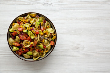 Homemade Grilled Corn Summer Pasta Salad in a Bowl on a white wooden background, top view. Flat lay, overhead, from above. Space for text.