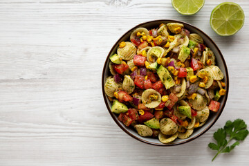 Homemade Grilled Corn Summer Pasta Salad in a Bowl on a white wooden background, top view. Flat lay, overhead, from above. Copy space.
