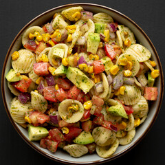 Homemade Grilled Corn Summer Pasta Salad in a Bowl on a black background, top view. Flat lay, overhead, from above. Close-up.