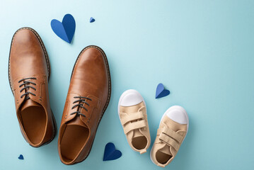 Father's Day celebration with little son. Top view of dad's leather shoes, son's sneakers, and hearts on pastel blue background with empty space