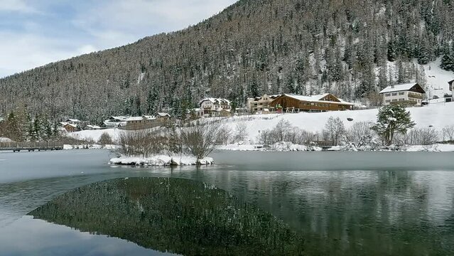 View of parts of Sulden from the little village pond during springtime. Everything's still covered with snow. Sulden, South Tyrol, Italy.