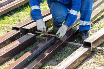 A worker in blue overalls works with metal pipes at a construction site