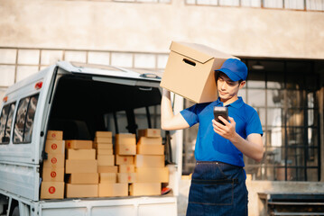Smiling delivery man standing in front of his van with Holding Box and tablet delivery home and shipping